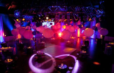 corporate ceiling decor with paper lanterns, hanging bands of drapes and pin spotted tables