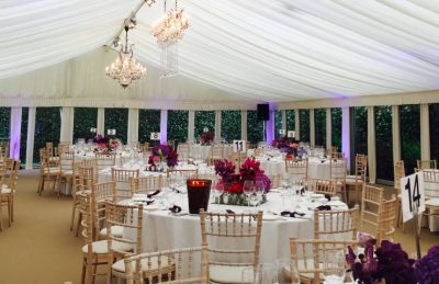 Marquee wedding interiors with white drapes, chiavary chairs and orchid center pieces