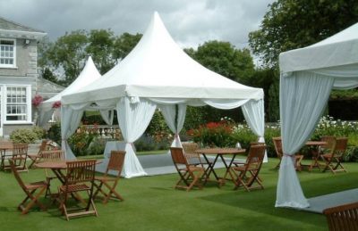 snow white pagodas for hire for wedding decor outdoors in a garden with wooden chairs and table