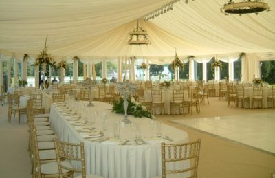 ivory wedding marquee drapery design with chandeliers and golden chiavary chairs