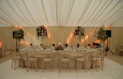 wedding top trestle table with hessian linen, floral arragements and white drapery on walls and ceiling