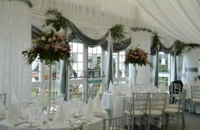 wedding marquee design with white and silver drapes and high red roses center pieces